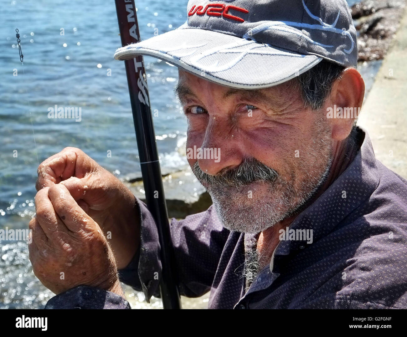 Mai 2016. Ein Porträt eines Mannes, Angeln an der Promanade am Hafen von Paphos, Südzypern. Stockfoto