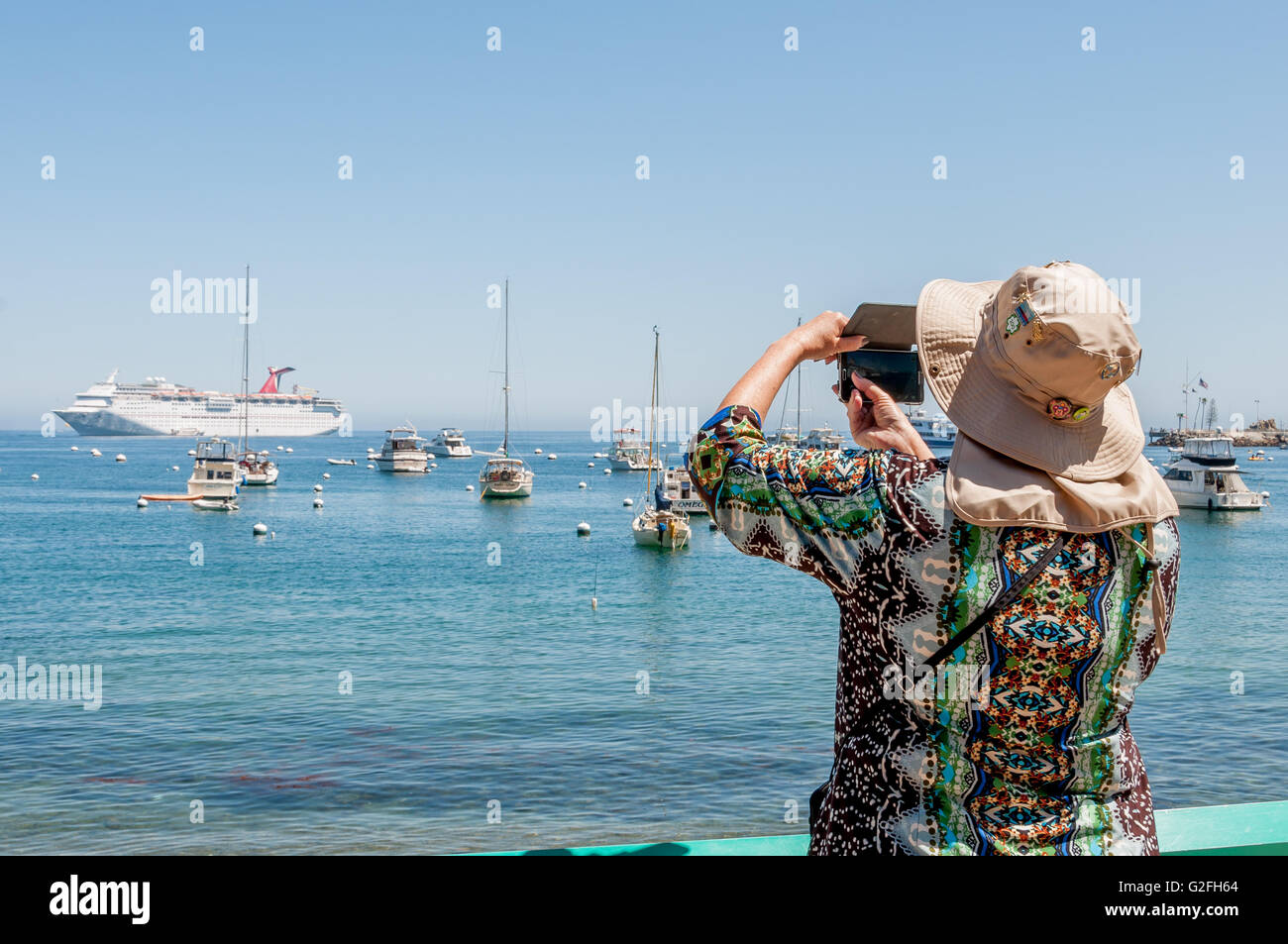 Frau Touristen nehmen Foto von Catalina Harbor w / Karneval Kreuzfahrtschiff in Avalon, Kalifornien, mit Smartphone für Reisen Foto Stockfoto