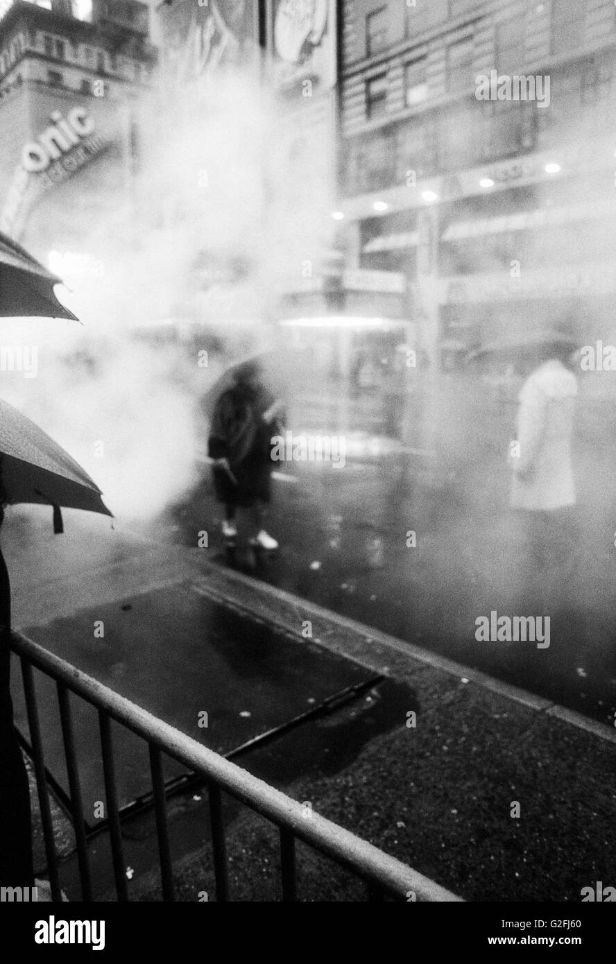 Menschen zu Fuß mit Sonnenschirmen in nebligen Regen, Times Square, New York City, USA Stockfoto
