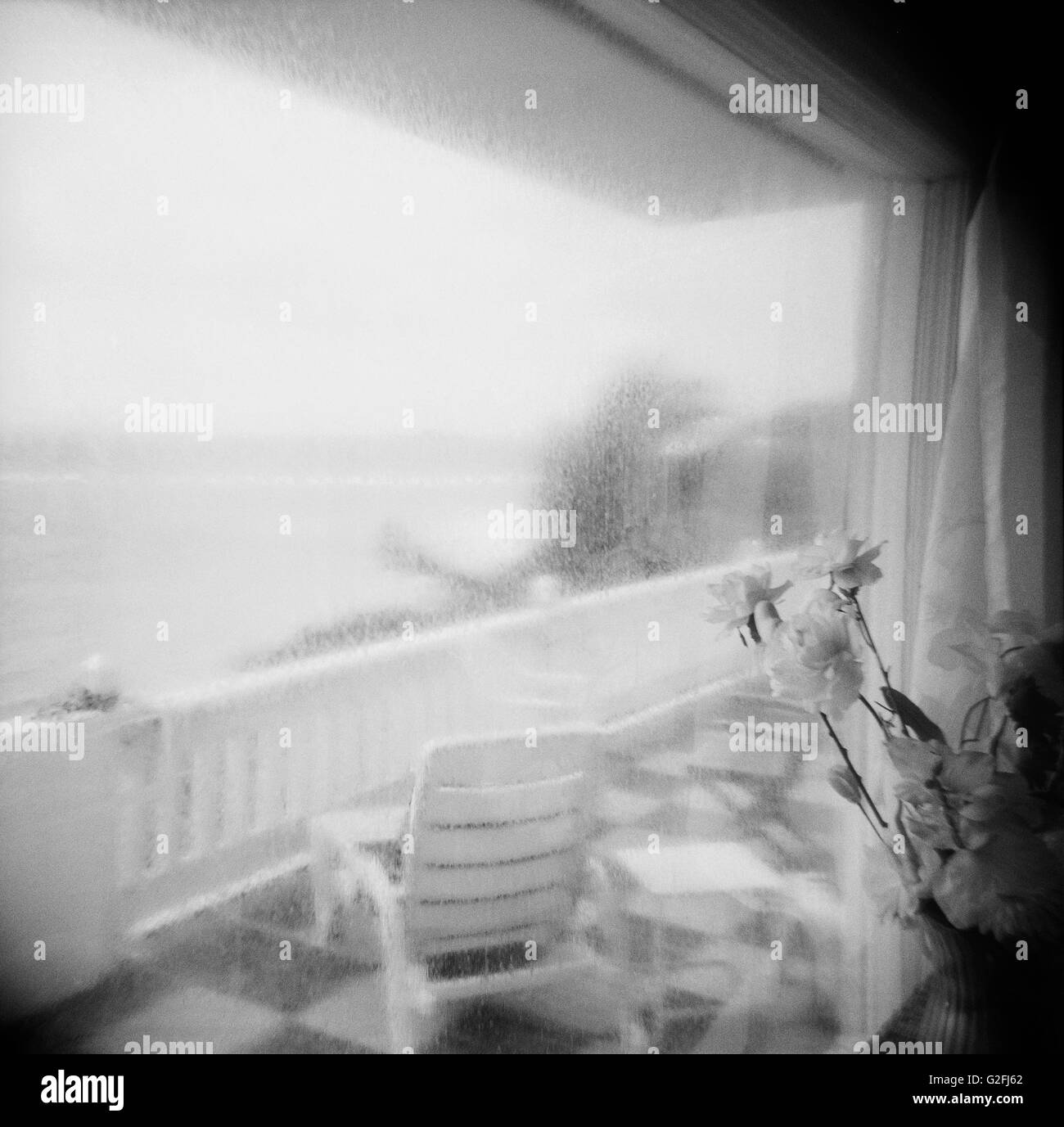 Verregneten Fenster mit Blumen mit Blick auf Terrasse und Meerblick Stockfoto