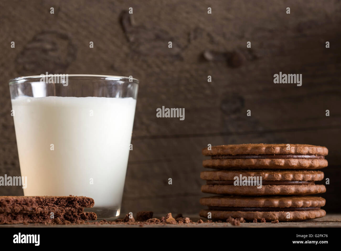 Ein Glas Milch mit Stapel Schokoladenkekse auf alten Holztisch Stockfoto