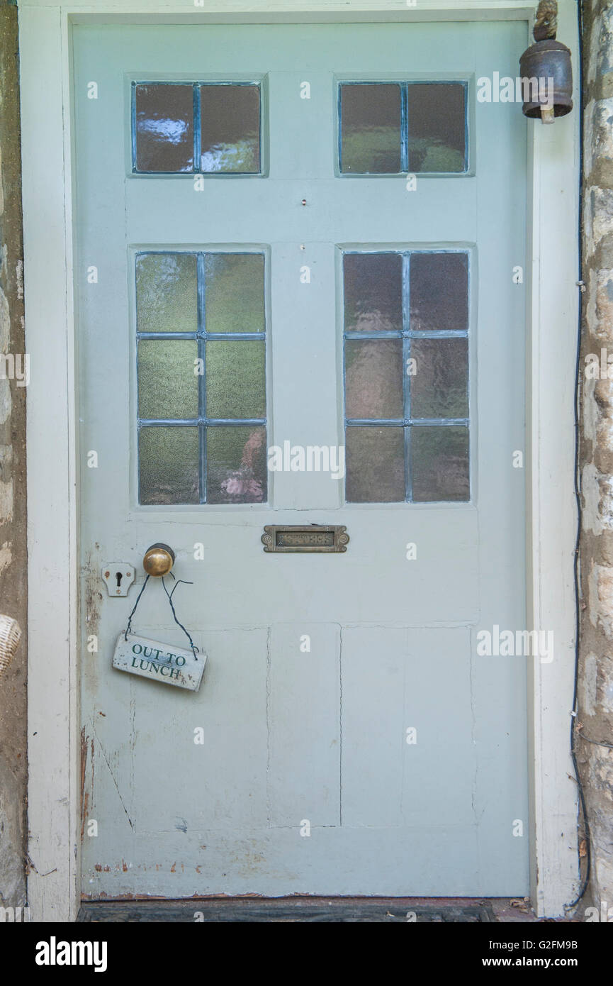 Eine Out to Lunch Zeichen aus einem alten viktorianischen Messing Türgriff hängt eine shabby chic Tür weiß lackiert mit vielen Dellen Stockfoto