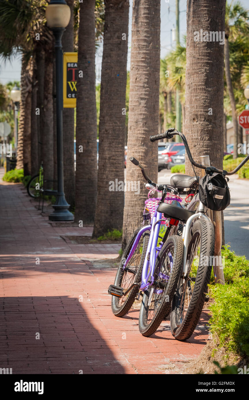 Fahrräder parken entlang einer Palm, von Bäumen gesäumten Straße vor Restaurants am Strand Gegend in Atlantic Beach, Florida. (USA) Stockfoto