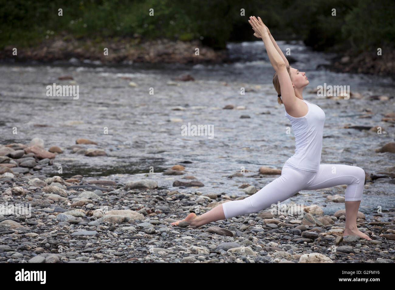 Junge Frau übt Yoga am Stein Ufer Fluss Stockfoto