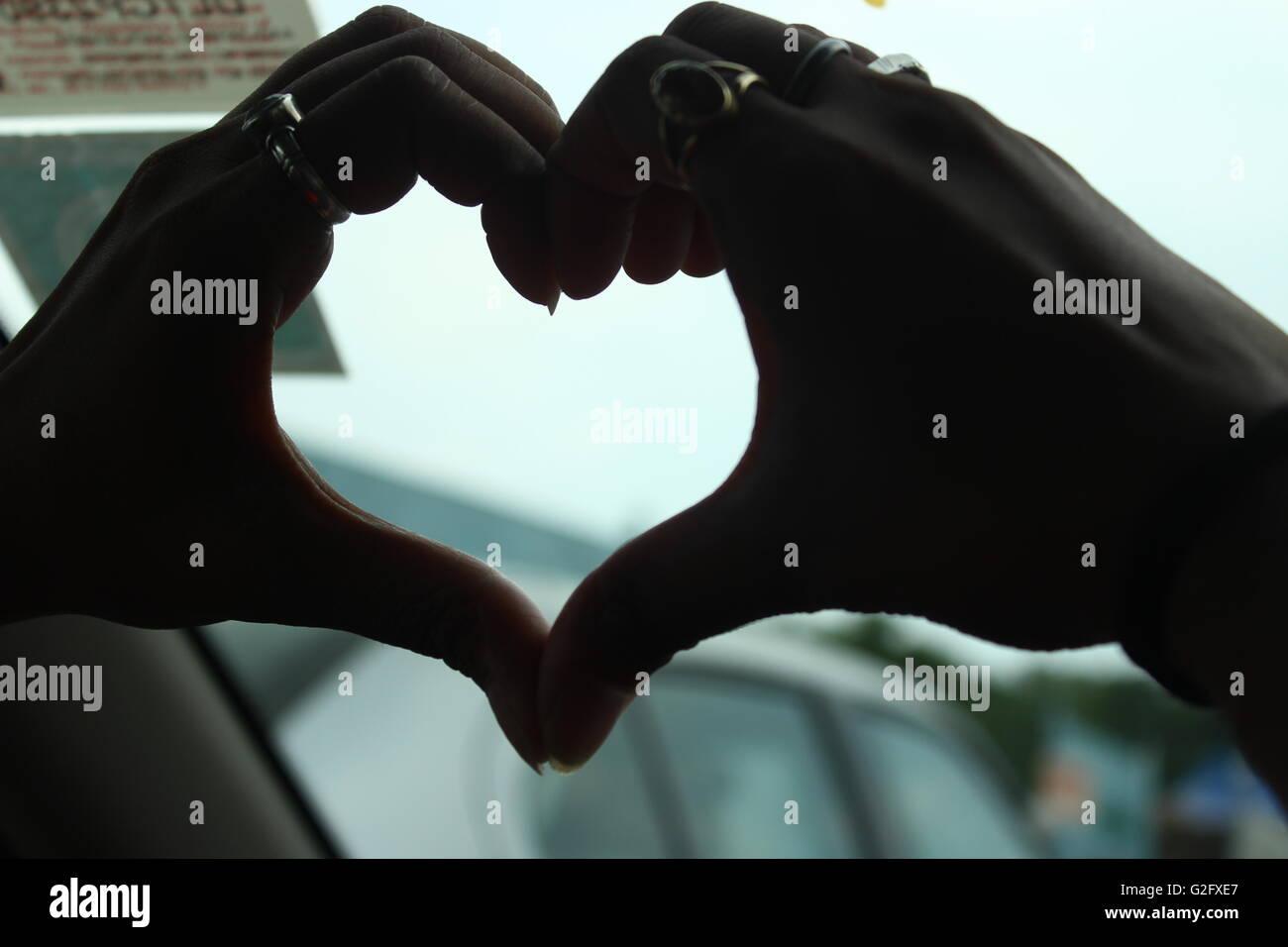 Ein Herzschild Form von Mädchen Hände im Auto mit hellen Hintergrund hinter der Hände oder des Herzens gemacht Stockfoto