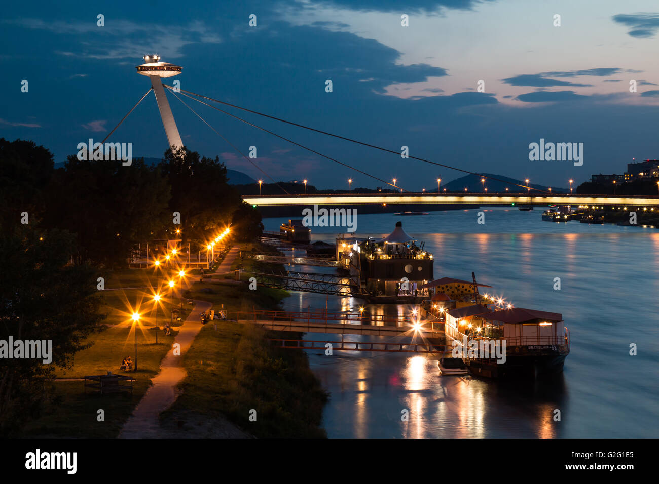 Blick auf die Brücke des slowakischen Nationalaufstand (oder UFO-Brücke). Donau mit Reflexionen. Wolkenhimmel Sonnenuntergang. Stockfoto