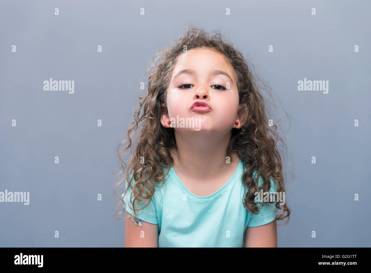 Porträt von kleinen Mädchen mit lockigen Haaren machen Luft Kuss auf Kamera. Studio gedreht Stockfoto
