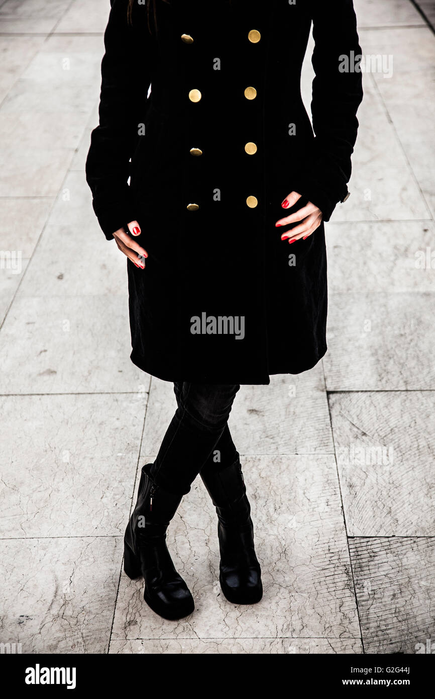 Frau trägt schwarzen Mantel mit goldenen Knöpfen und schwarzen Stiefeln,  Nahaufnahme von Torso-Down Stockfotografie - Alamy