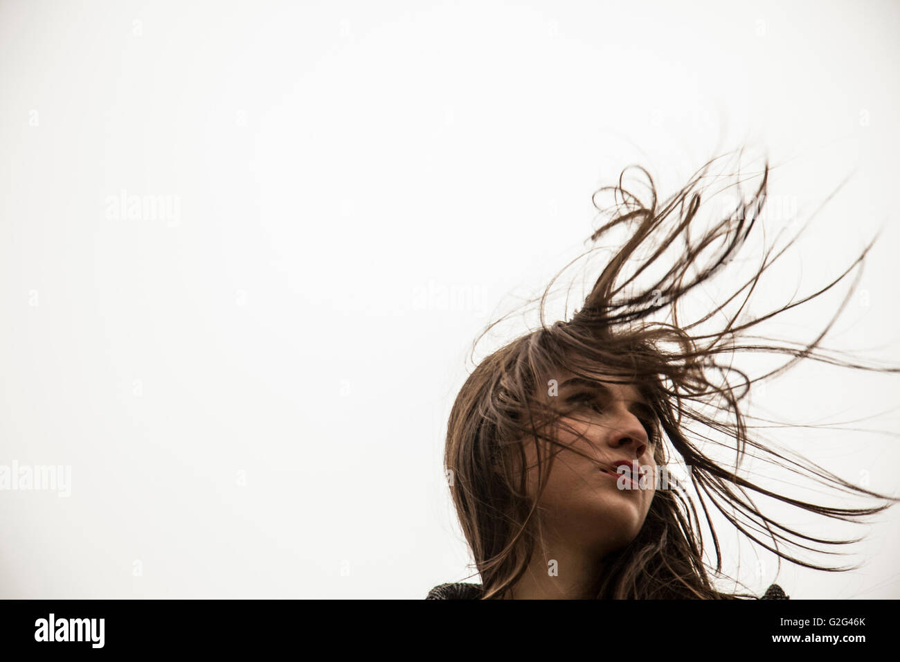 Portrait of Young Adult Woman mit Haar weht im Wind, Low Angle View Stockfoto
