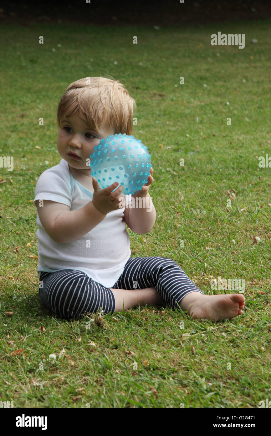 Baby Boy mit Ball spielen auf Rasen Stockfoto