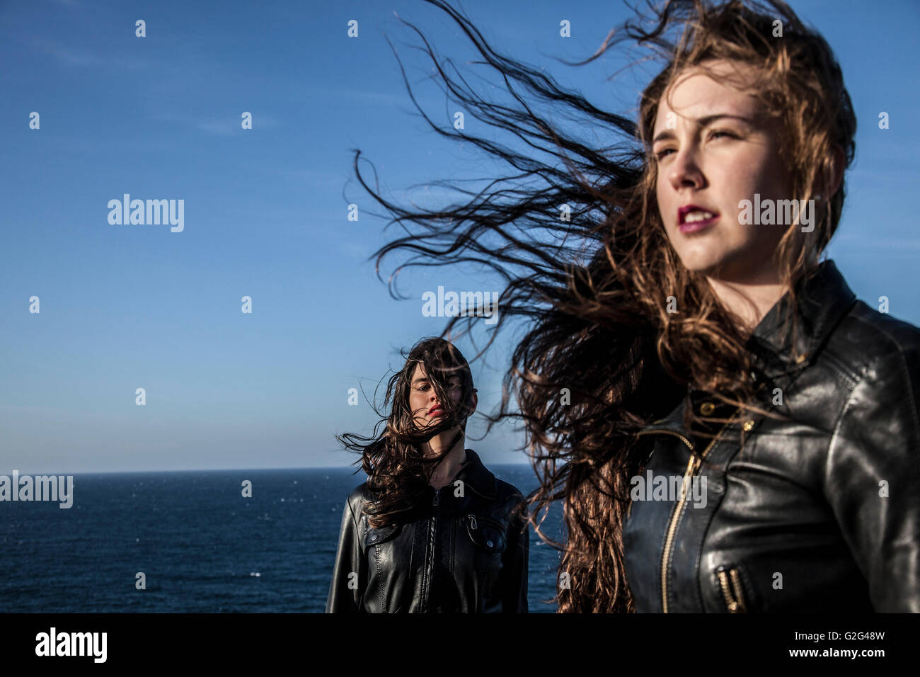 Zwei junge Frauen mit Haar im Wind vom Meer Stockfoto