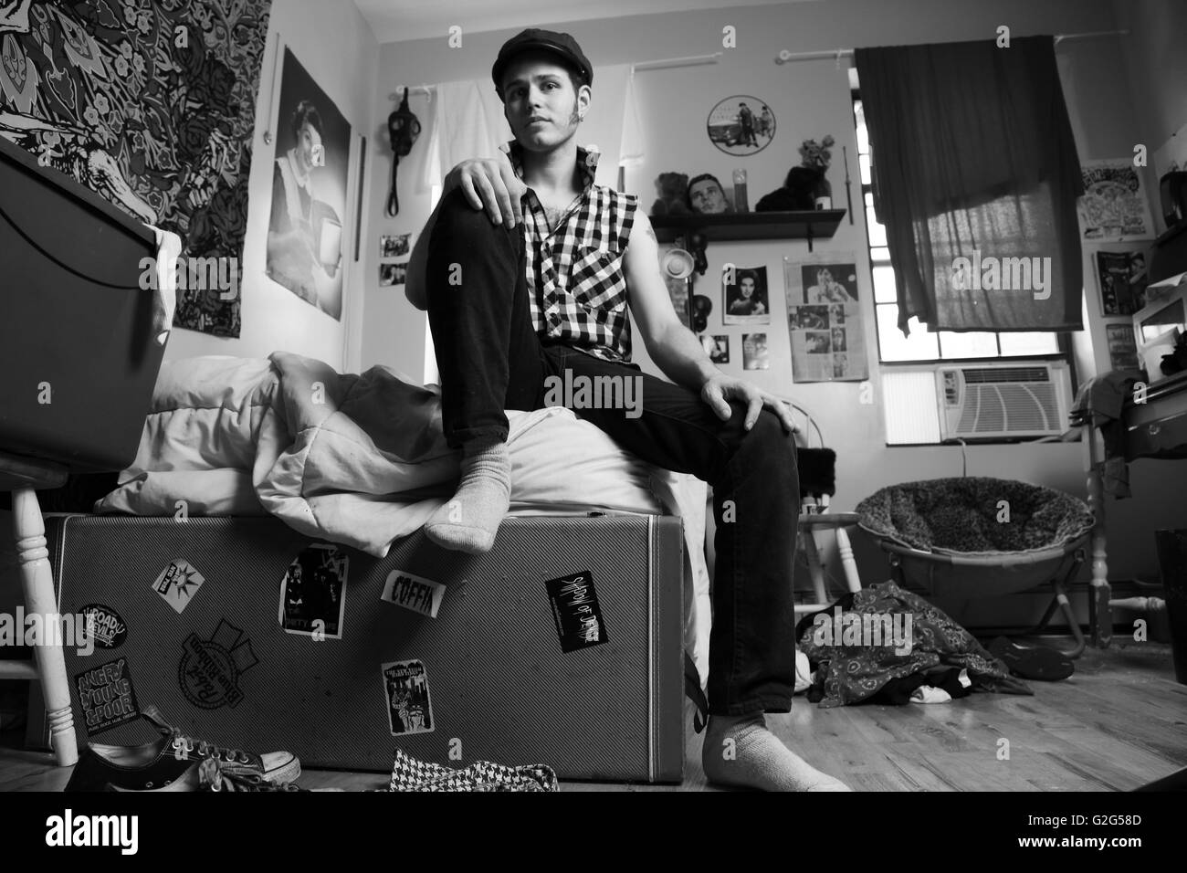 Junger Mann sitzt im unordentlichen Zimmer, Porträt Stockfoto