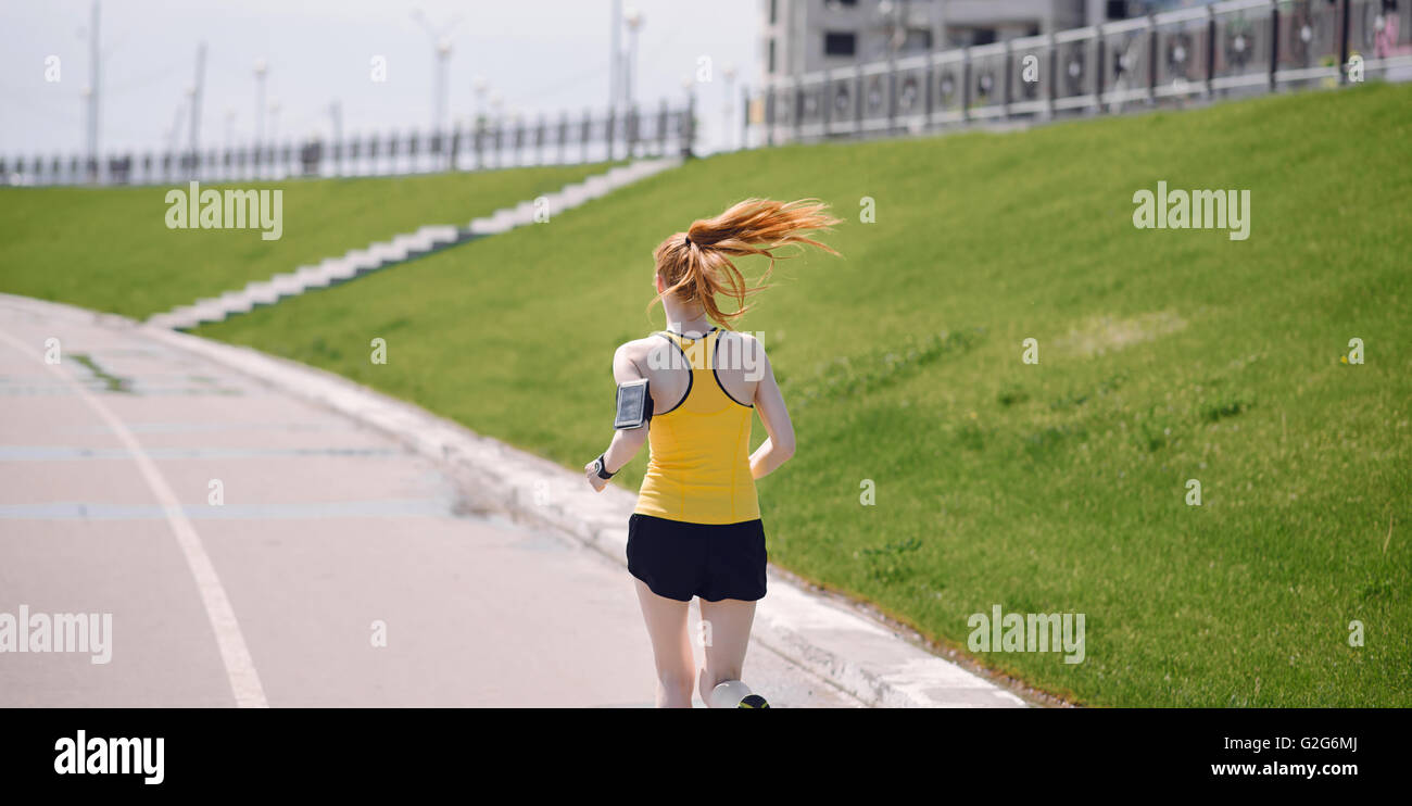 Junge gesunde Lebensweise Frau läuft bei Sonnenaufgang Road. Mädchen laufen auf Asphaltstraße. Mädchen läuft in gelb Sport-shirt Stockfoto