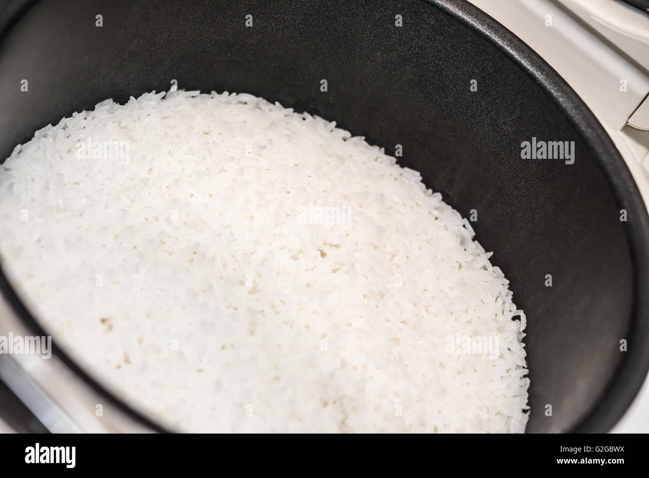 Reis in den inneren Topf mit elektrischer Reiskocher Stockfoto