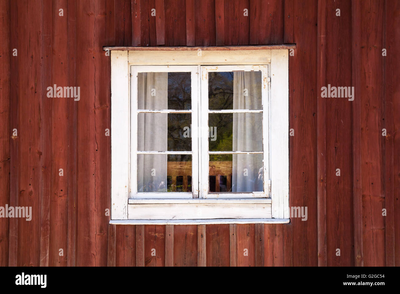 Alte dunkle rote Holzwand mit Fenster in weißer Rahmen, typisch skandinavisch Leben Haus Architektur Detail Stockfoto