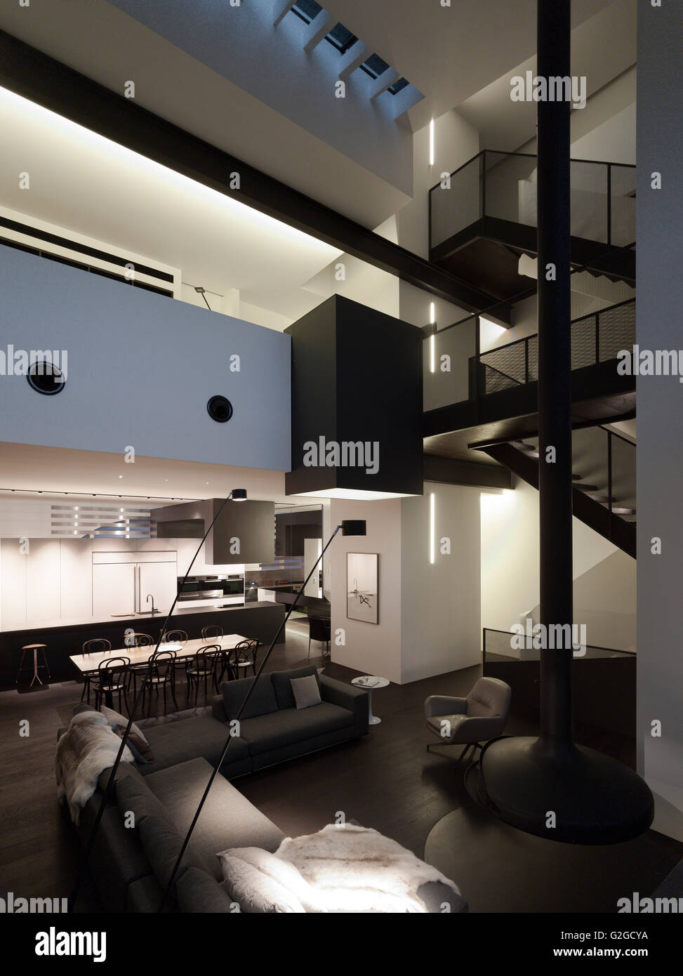 Überblick über Wohnzimmer, Esszimmer, Küche, Treppen und oberen Ebenen in der Abenddämmerung. W-House, Sydney, Australien. Architekt: MCK Architekten, 2015. Stockfoto