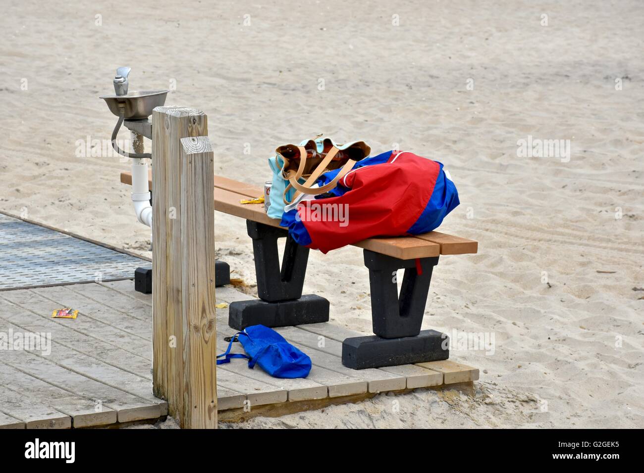 Artikel von Kleidung und persönliche Gegenstände überlassen auf einer Bank als nächstes eine Wasserfontäne am Strand im Assateague island Stockfoto