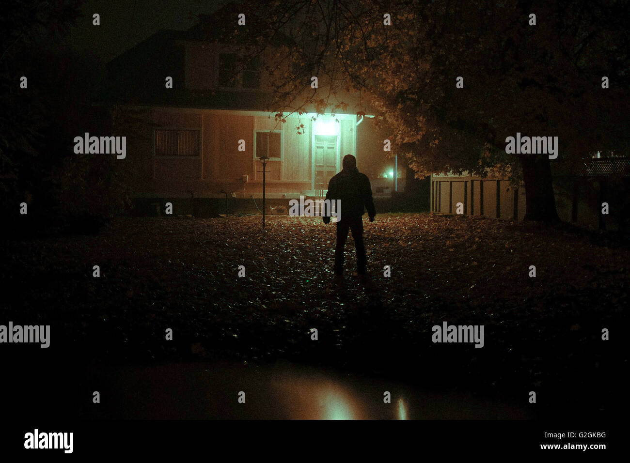 Geheimnisvoller Mann Blick auf Haus aus Hinterhof in der Nacht Stockfoto