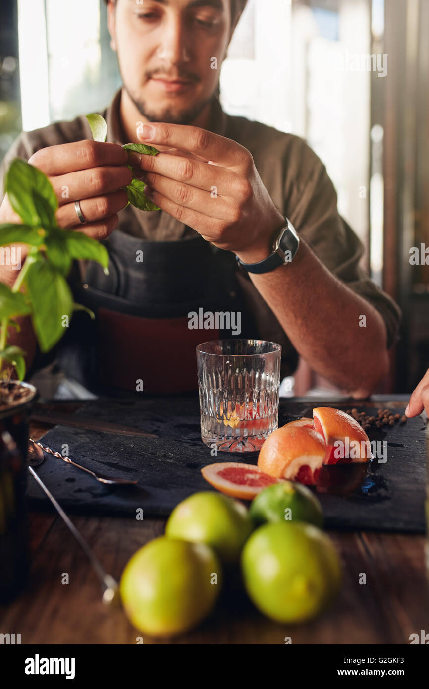 Cocktail Zubereitung Zutaten auf Tisch mit Barkeeper hält Basilikumblätter. Stockfoto