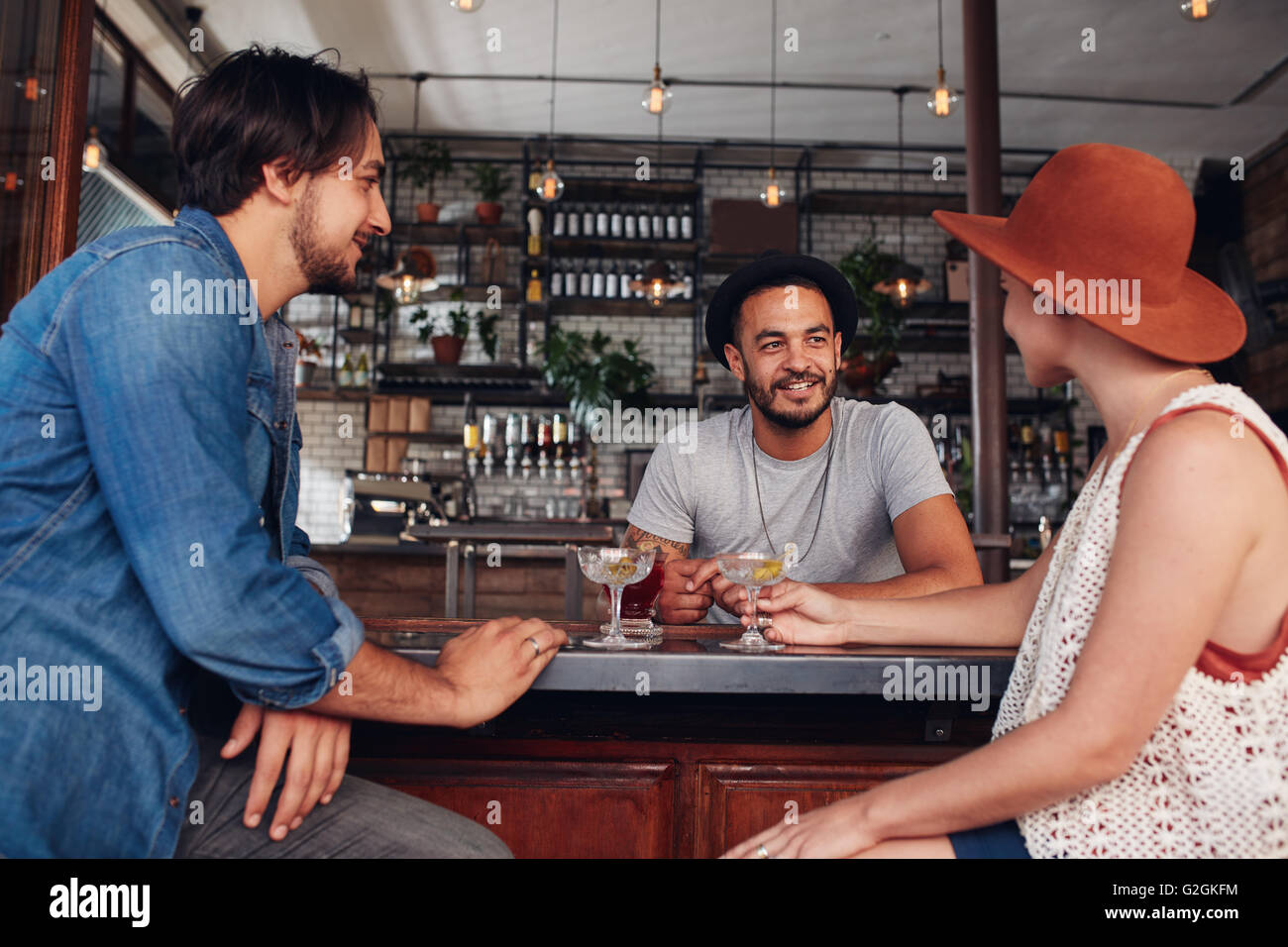 Drei junge Freunde lächelnd und sitzen in einem Café mit Getränken zusammen. Moderne Jugendliche sitzen in den Coffee-Shop und hav Stockfoto
