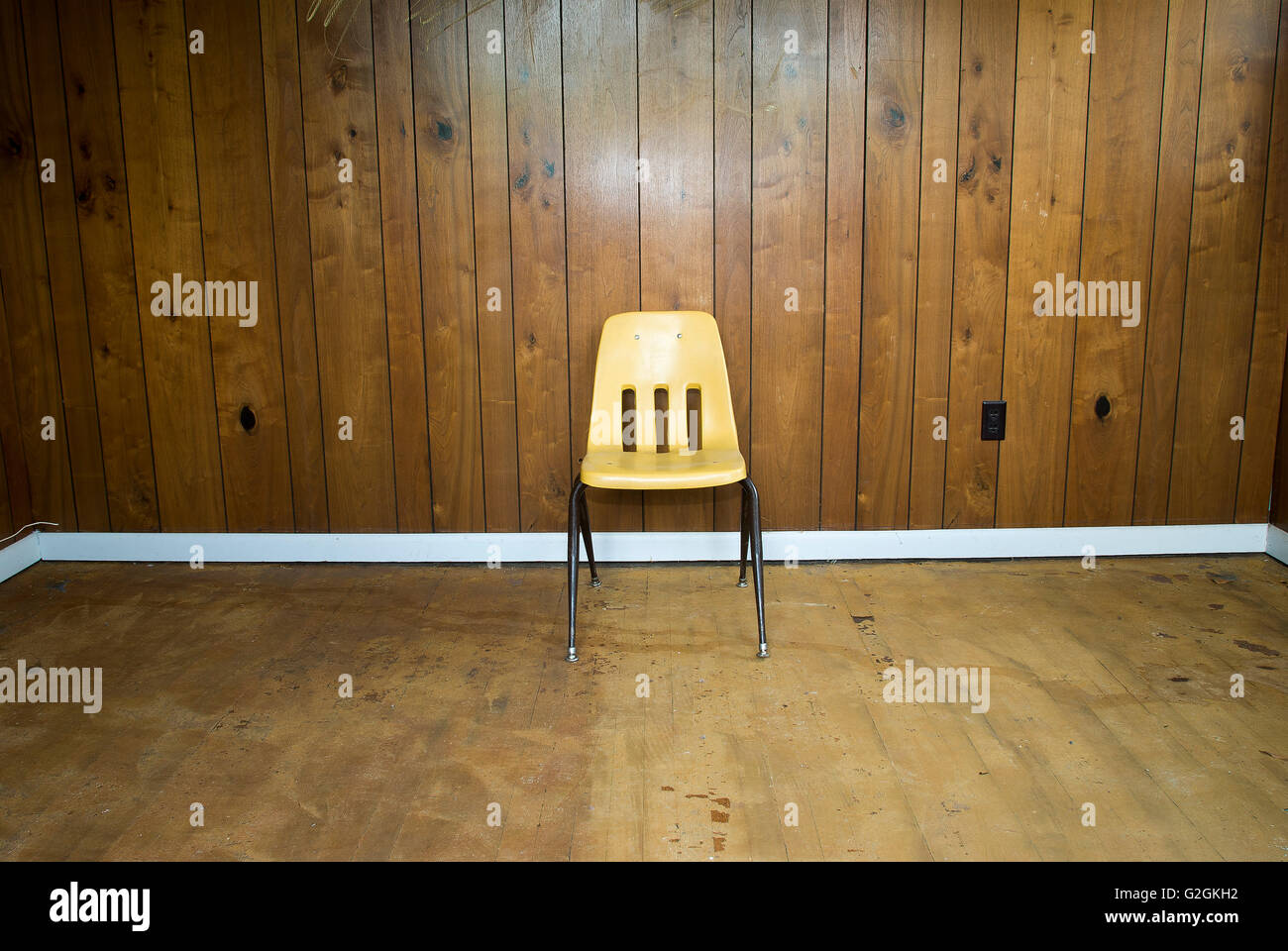 Gelber Stuhl mit Holzverkleidung an Wand Stockfoto