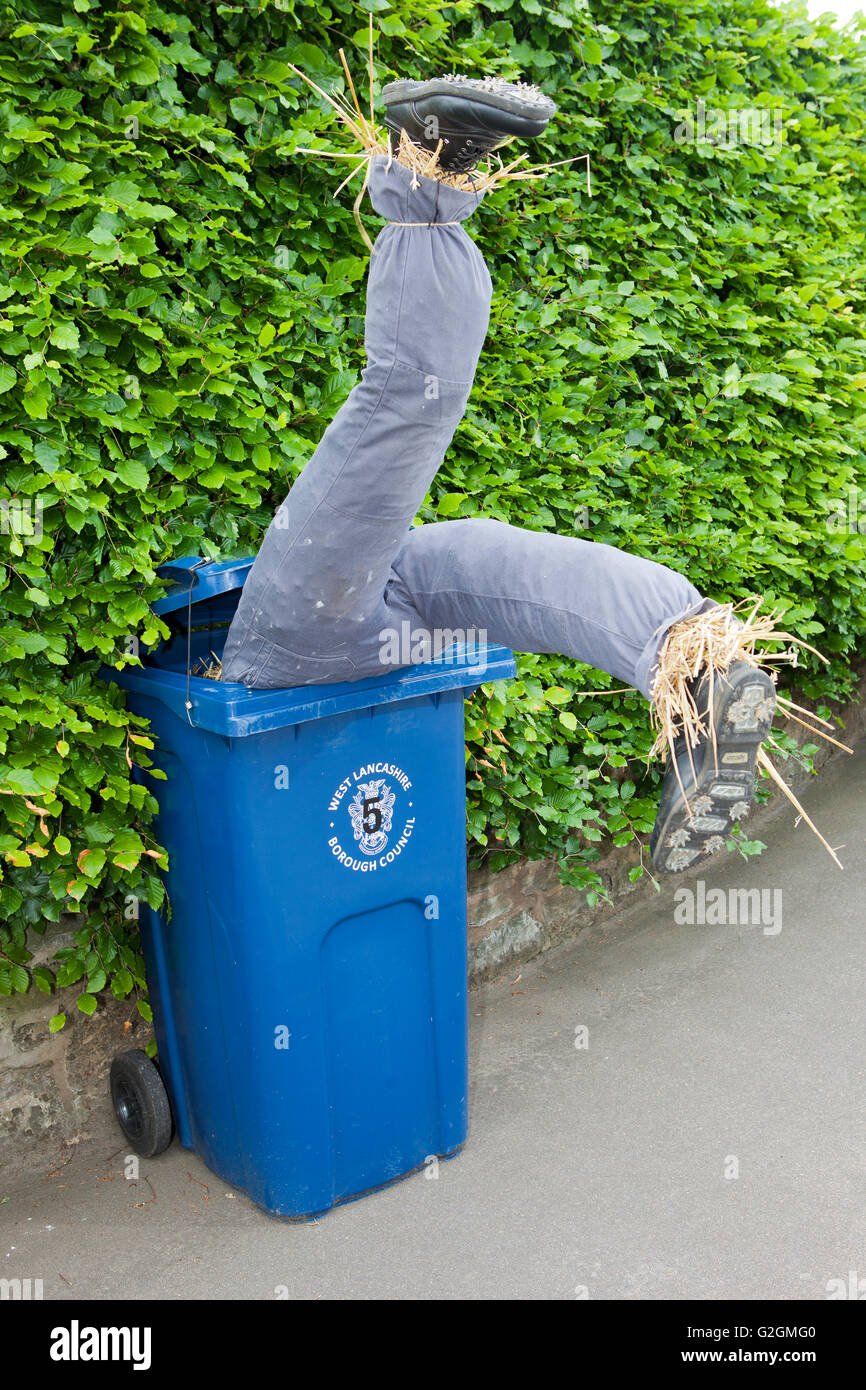 Vogelscheuche aus Stroh hochkant im Wheelie bin, mit den Beinen in der Luft, auf der Suche nach verlorenen Gegenstände. Southport, Merseyside, UK Stockfoto