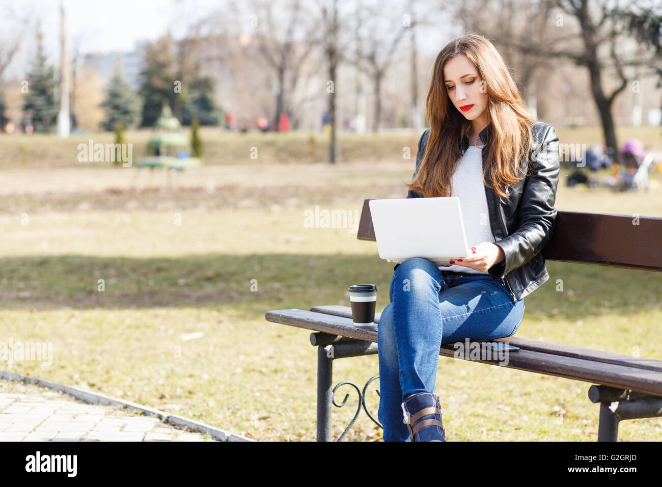 Junge Geschäftsfrau mit Laptop auf der Parkbank sitzen. Europäische lächelnd Studentin mit Notebook lesen oder lernen ich Stockfoto