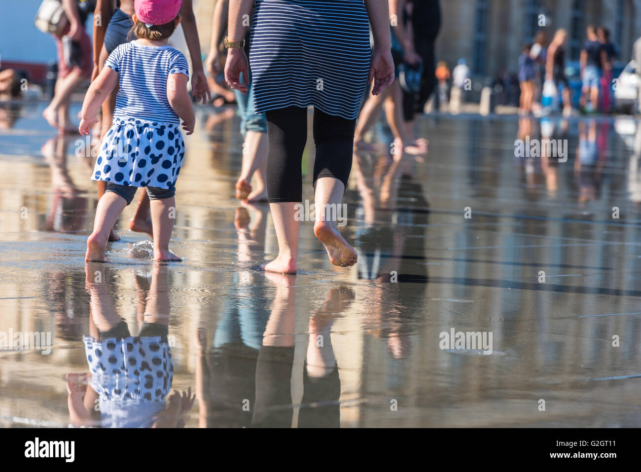 Leute, die Spaß in einem Spiegel-Brunnen vor dem Place De La Bourse in Bordeaux, Frankreich Stockfoto