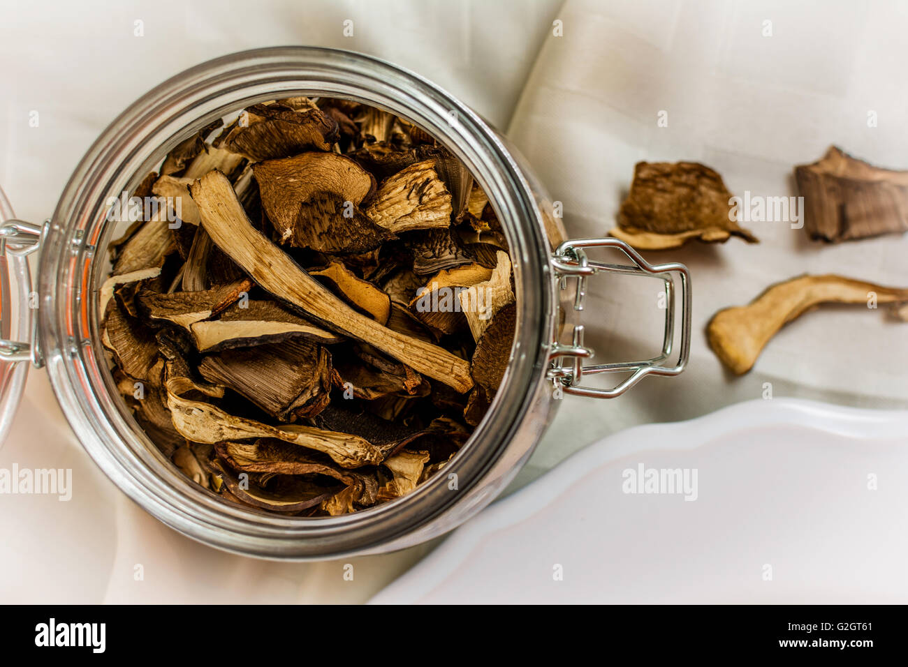 Getrocknete Pilze in Glasflasche auf dem weißen Tuch Stockfoto