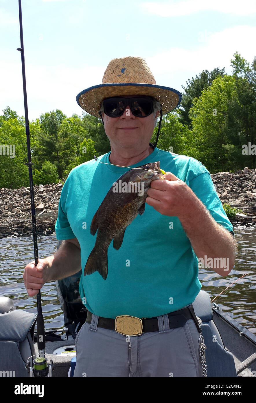 Fischer-Porträt eines Fischers, hält eine kleine Mund Bass stehen in einem Boot Stockfoto