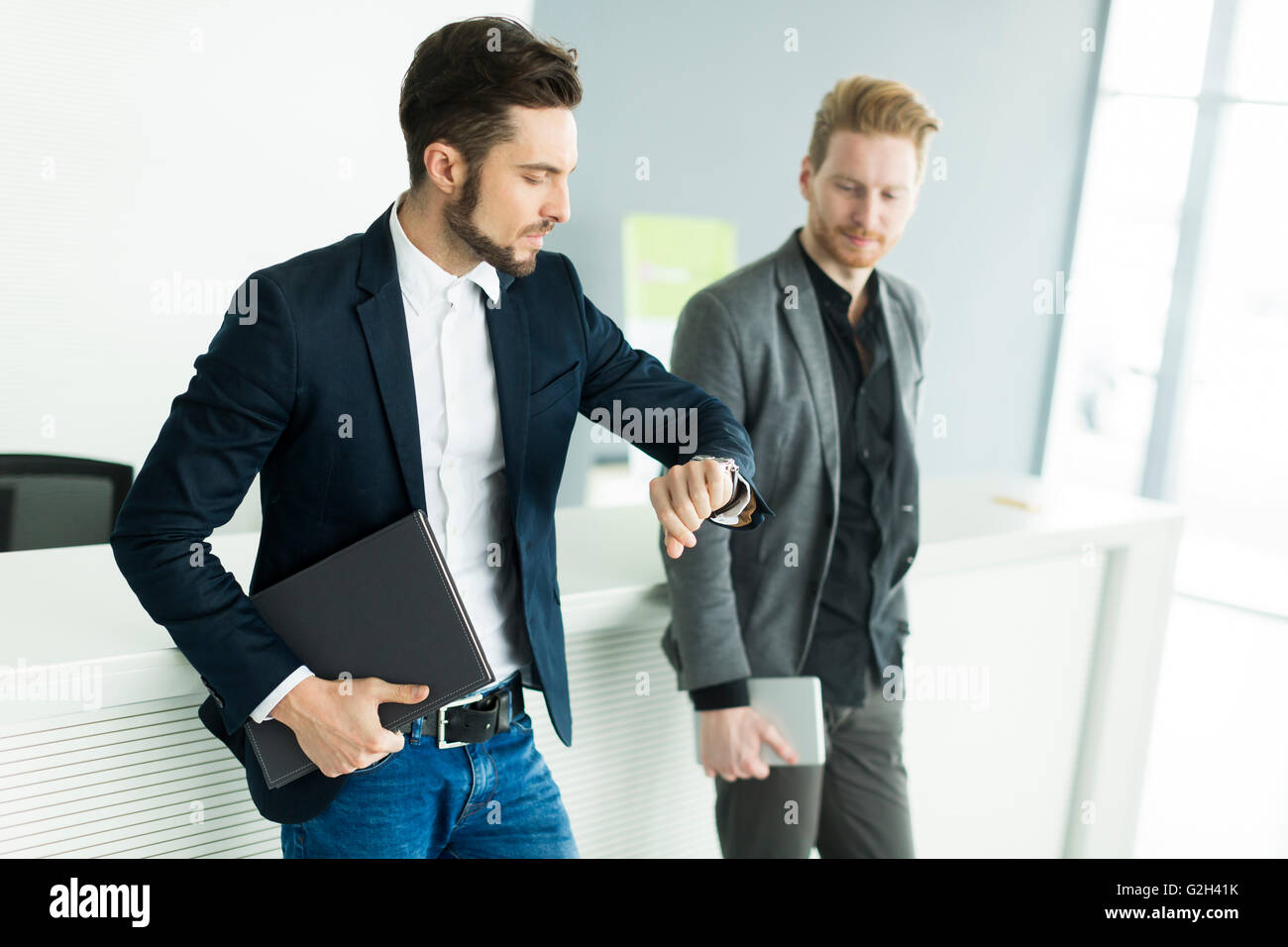 Zwei junge Männer mit Tablet und Datei im modernen Büro Stockfoto