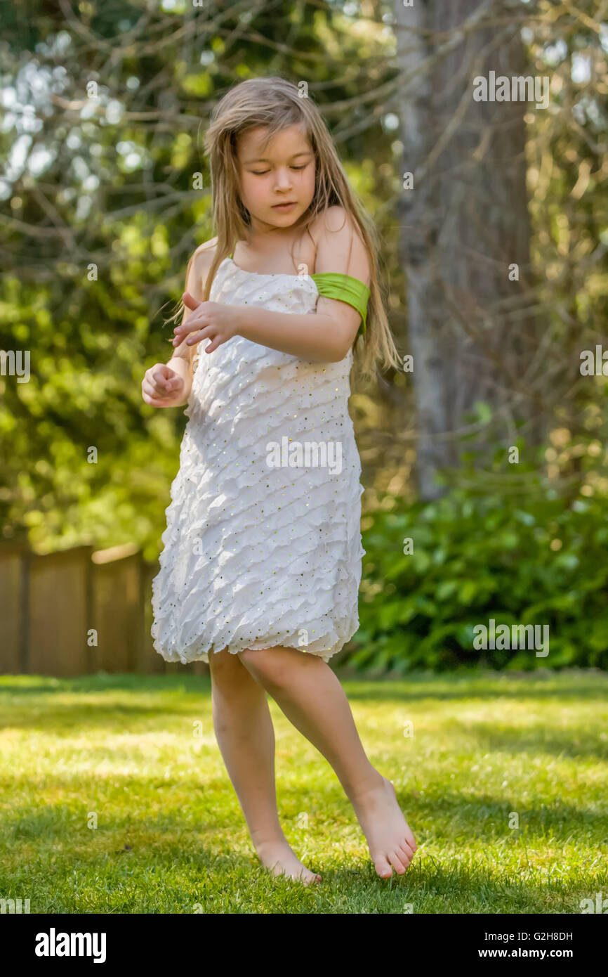 Sieben Jahre altes Mädchen schüchtern tanzen in ihrem Hinterhof in Issaquah, Washington, USA Stockfoto