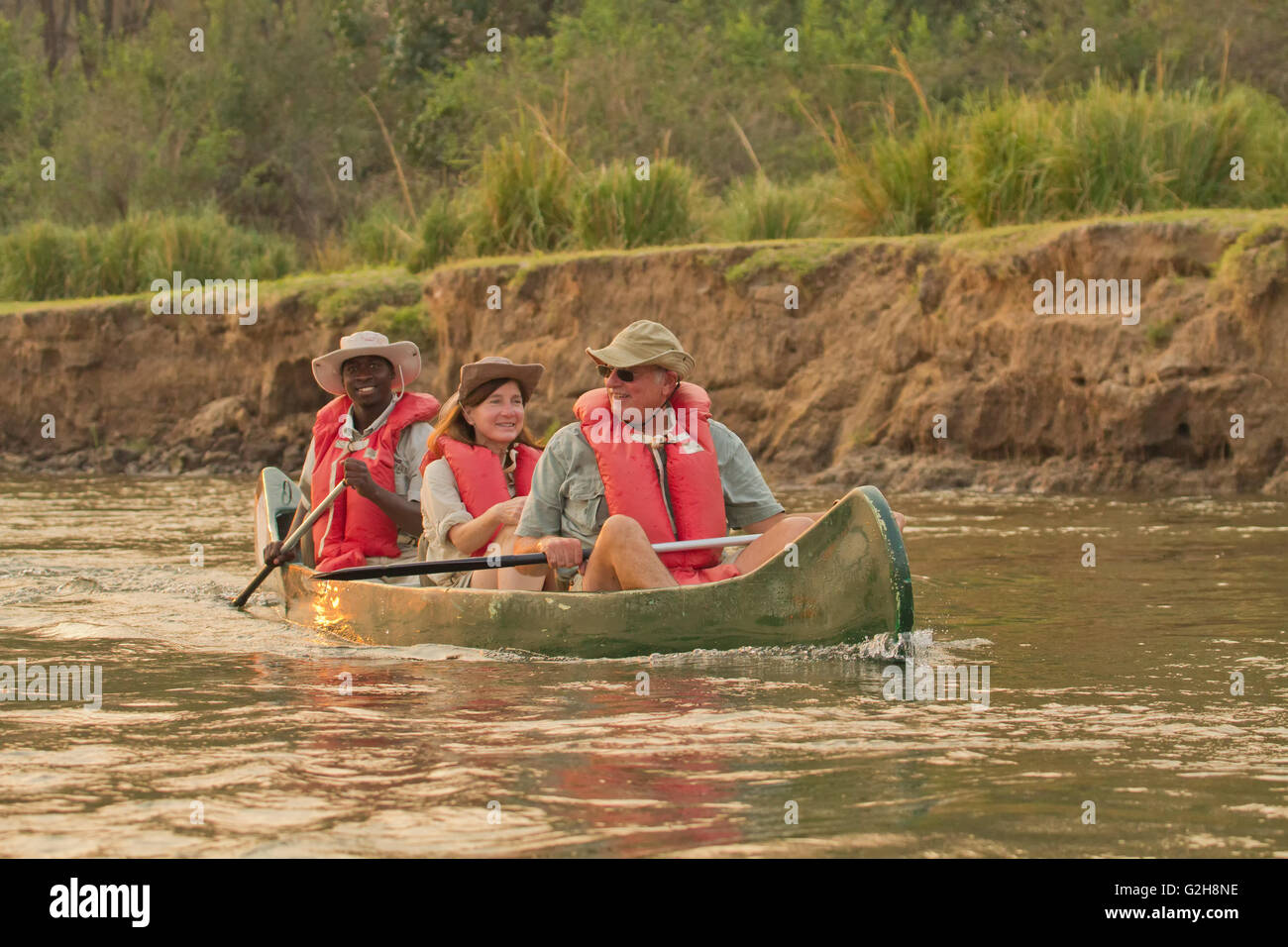 Afrikanische Safari-Guide und Touristen paddeln Kanu auf dem Sambesi-Fluss in der Nähe von Lower Zambezi National Park, Sambia, Afrika Stockfoto