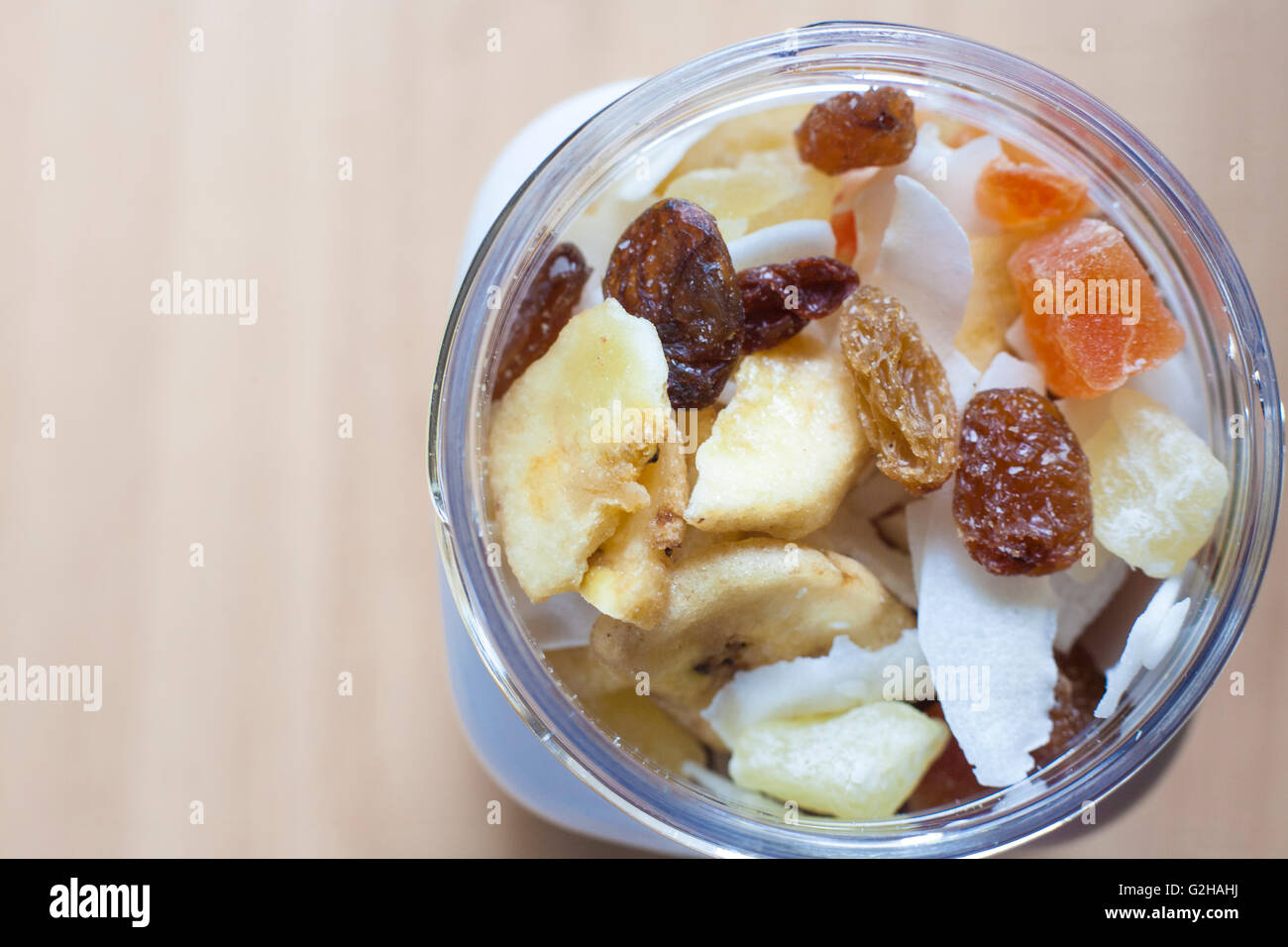 Kunststoff-Glas mit gemischte Trockenfrüchte über Holzoberfläche. Selektiven Fokus. Erhöhte Ansicht Stockfoto