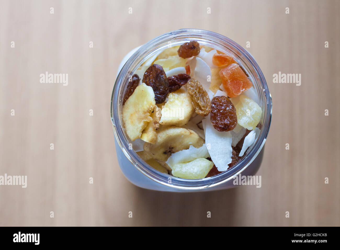 Kunststoff-Glas mit gemischte Trockenfrüchte über Holzoberfläche. Selektiven Fokus. Erhöhte Ansicht Stockfoto