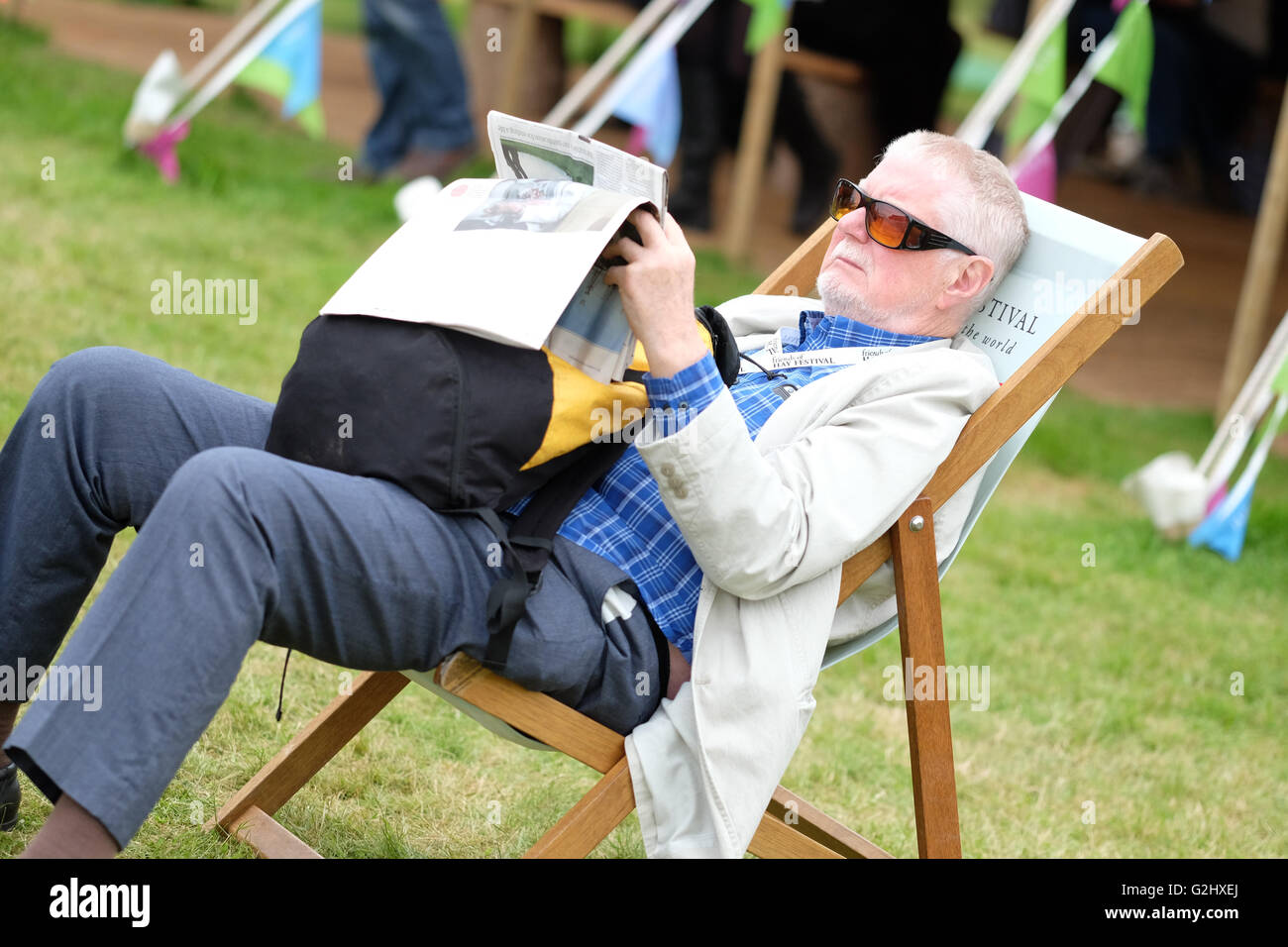 Hay Festival, Wales, Großbritannien - Juni 2016 - der Besucher findet Zeit, zu sitzen und seine Zeitung auf dem Heu Book Festival Rasenflächen zwischen den Veranstaltungen und Sitzungen zu lesen. Stockfoto