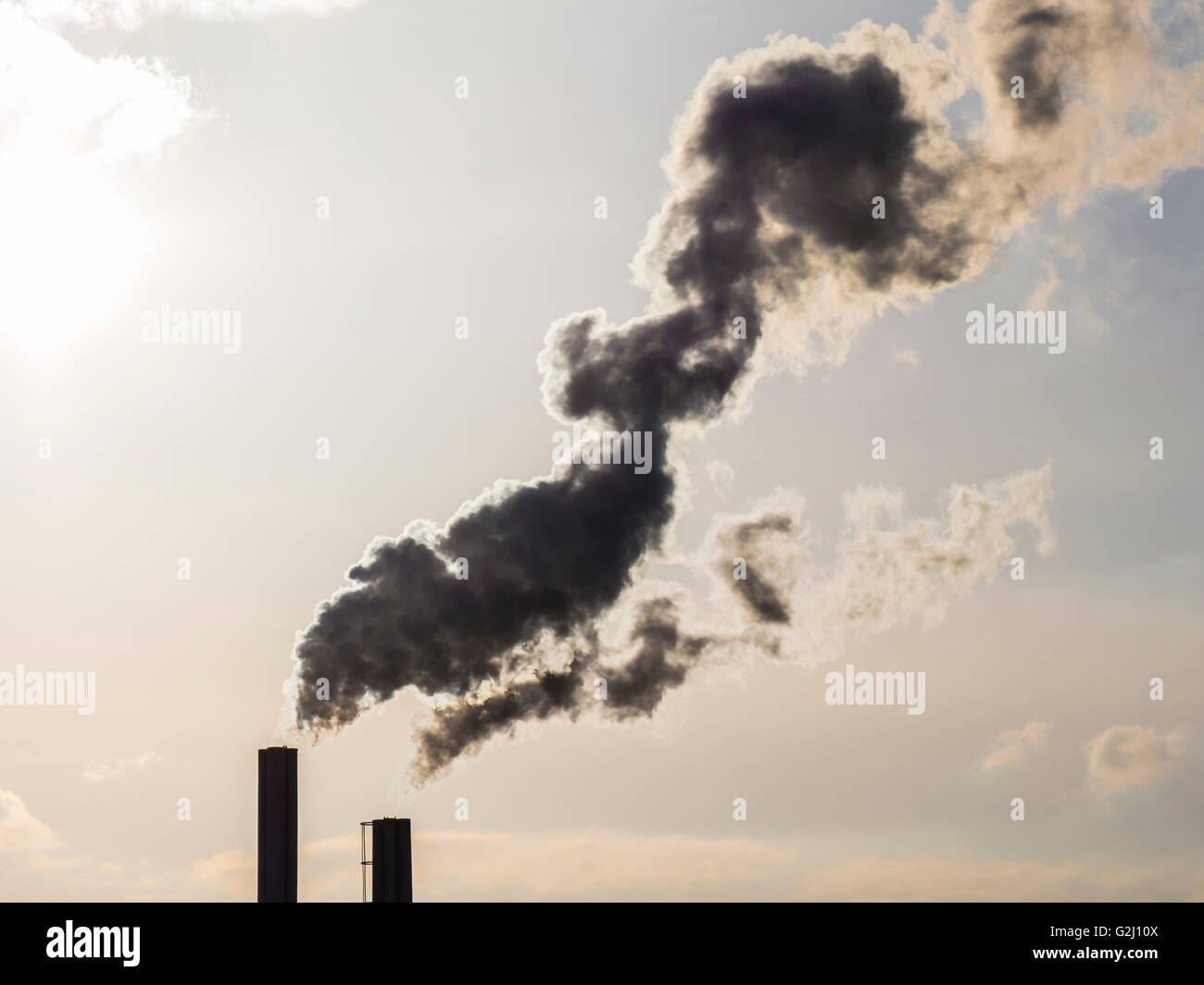 Schornsteine mit Rauchwolken im Gegenlicht, Factory, Celle, Deutschland Stockfoto