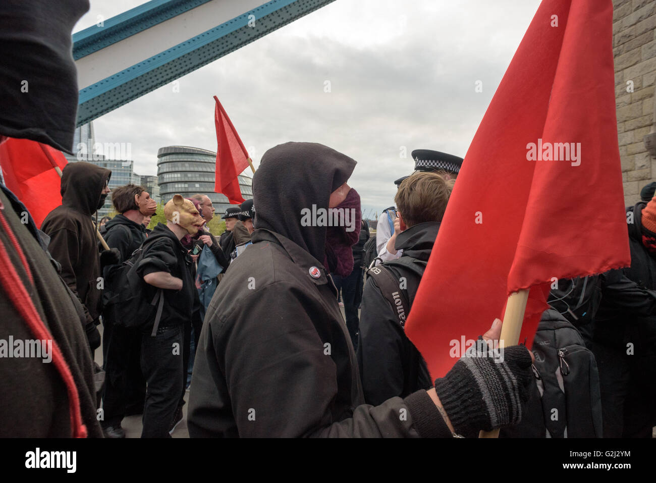 May Day anarchistische Gruppe, mit versteckten Gesichtern, Parolen und roten Fahnen zu Fuß über die Tower Bridge 1. Mai 2016 Stockfoto