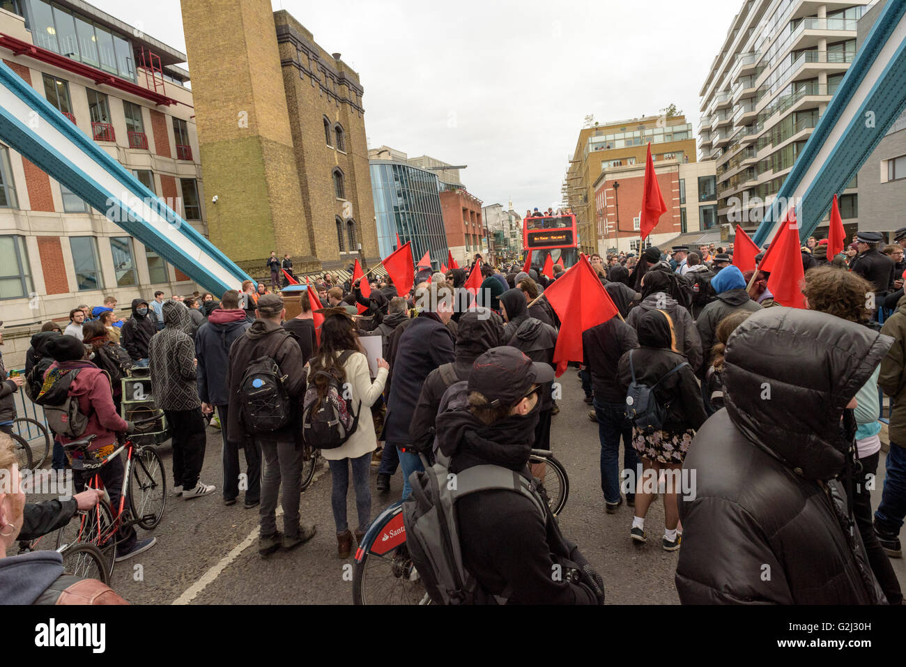 May Day anarchistische Gruppe, mit versteckten Gesichtern, Parolen und roten Fahnen zu Fuß über die Tower Bridge 1. Mai 2016 Stockfoto