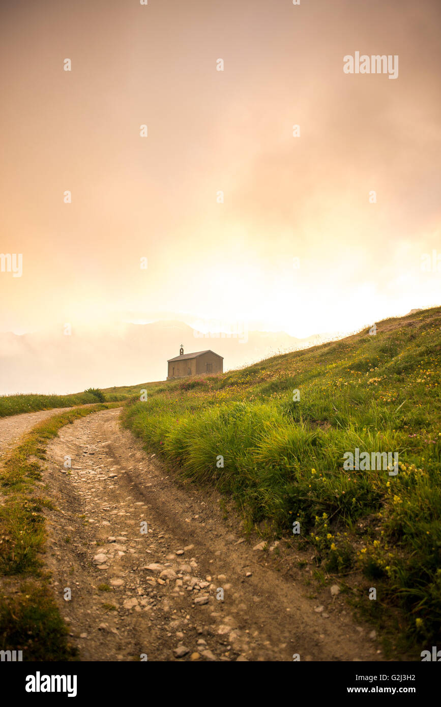 Ländliche unbefestigte Straße führt zur Kirche bei Sonnenaufgang Stockfoto