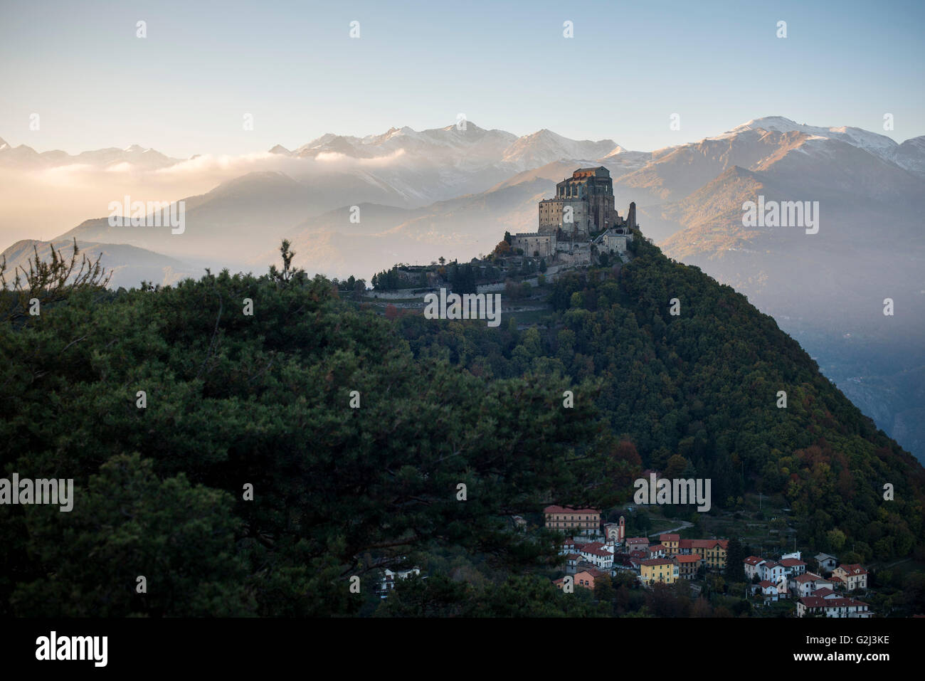 Sacra di San Michele bei Sonnenuntergang mit Alpen im Hintergrund und Dorf San Pietro unten, Italien Stockfoto