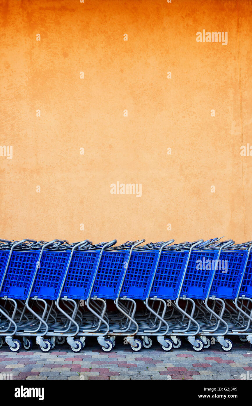 Linie der Einkaufswagen gegen bunte Wand blau Stockfoto