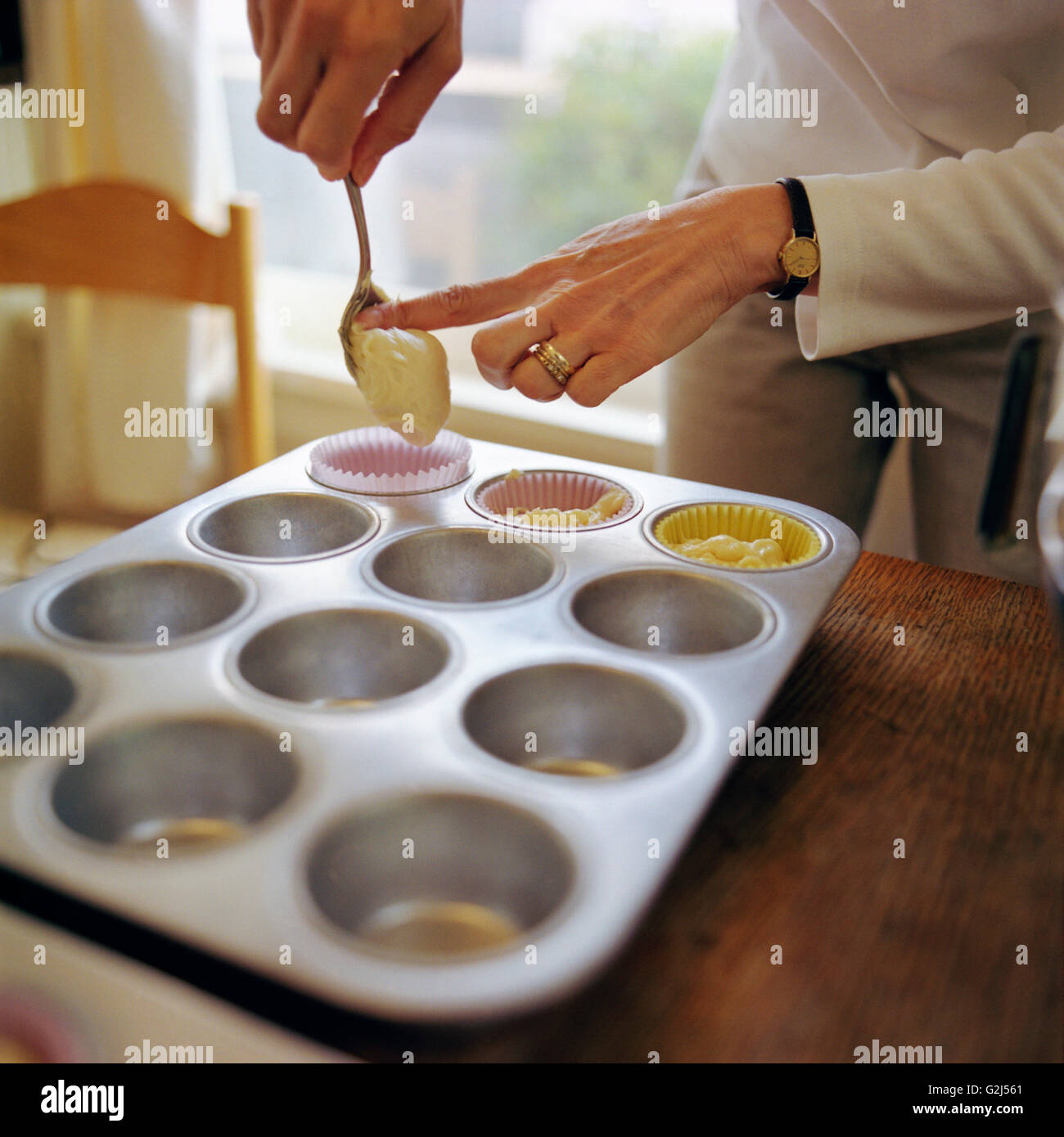 Frau Muffinblech mit Teig füllen Stockfoto