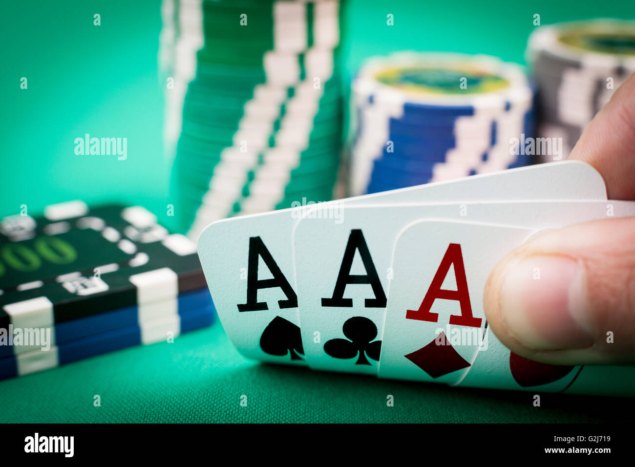 Vier Asse in der Hand mit Casino-Chips in der Zeitmessung auf grün Stockfoto