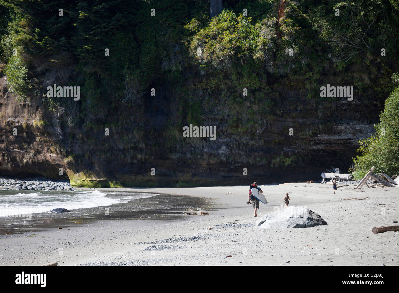 Ein Mann geht mit einem Surfbrett und zwei Kindern am China Beach in der Juan de Fuca Provincal Park Vancouver Island BC Kanada. Stockfoto