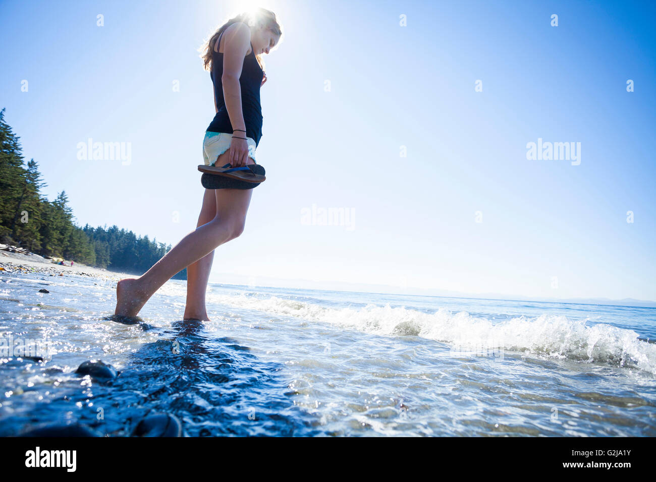 Eine junge Frau steht barfuß im Ozean in Französisch Beach Provincial Park. Vancouver Island, BC, Kanada Stockfoto