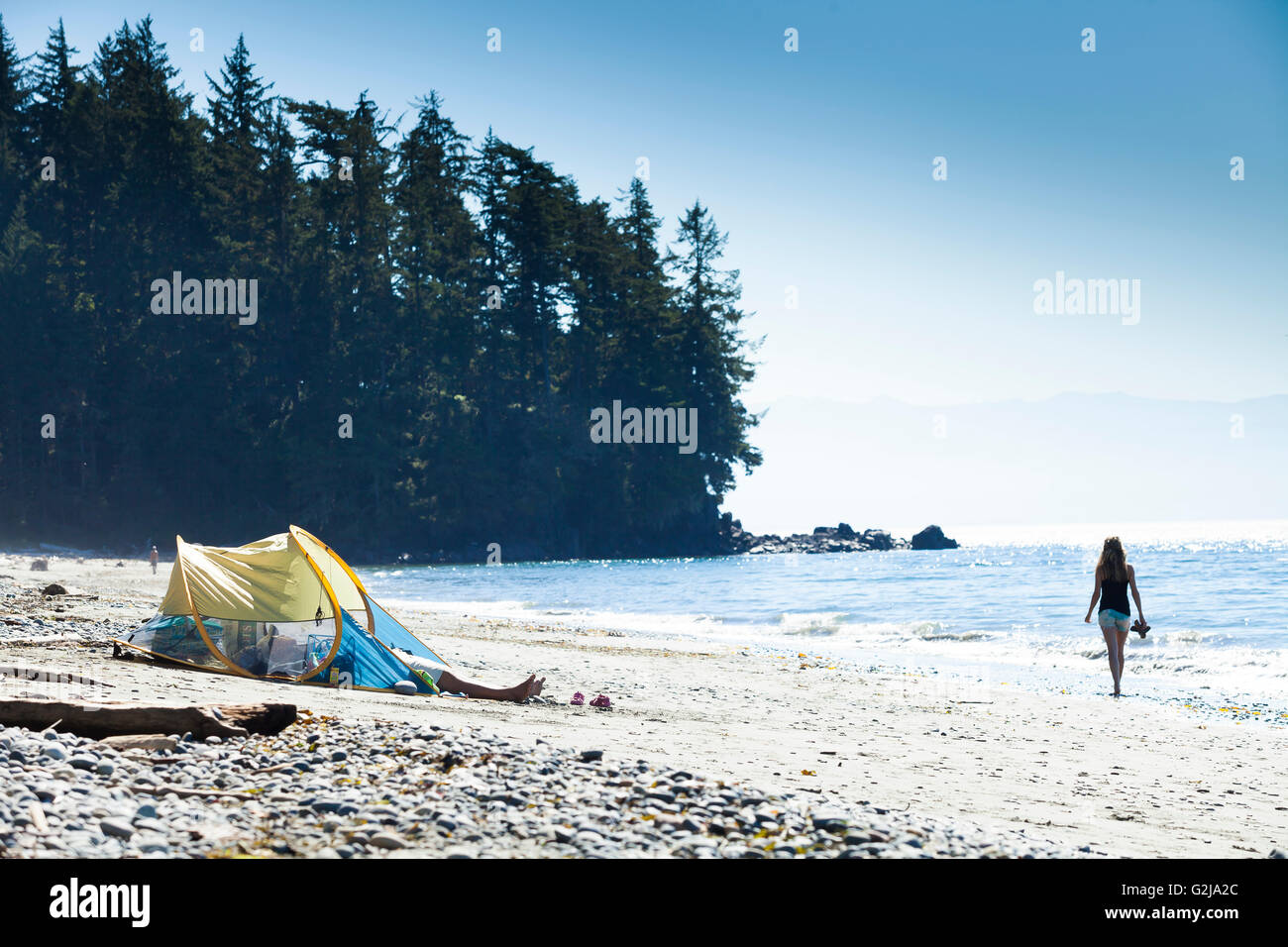 Eine junge Frau geht barfuß am Strand am französischen Beach Provincial Park entlang. Vancouver Island, BC, Kanada. Stockfoto