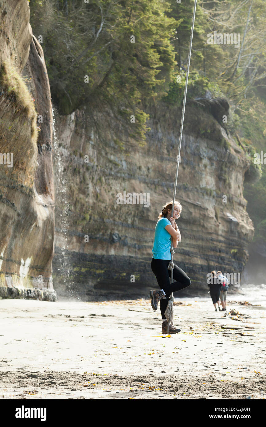 Eine junge Frau schwingt auf einem Seil schwingen im Mystic Beach entlang der Juan de Fuca Trail. Vancouver Island, BC, Kanada. Stockfoto