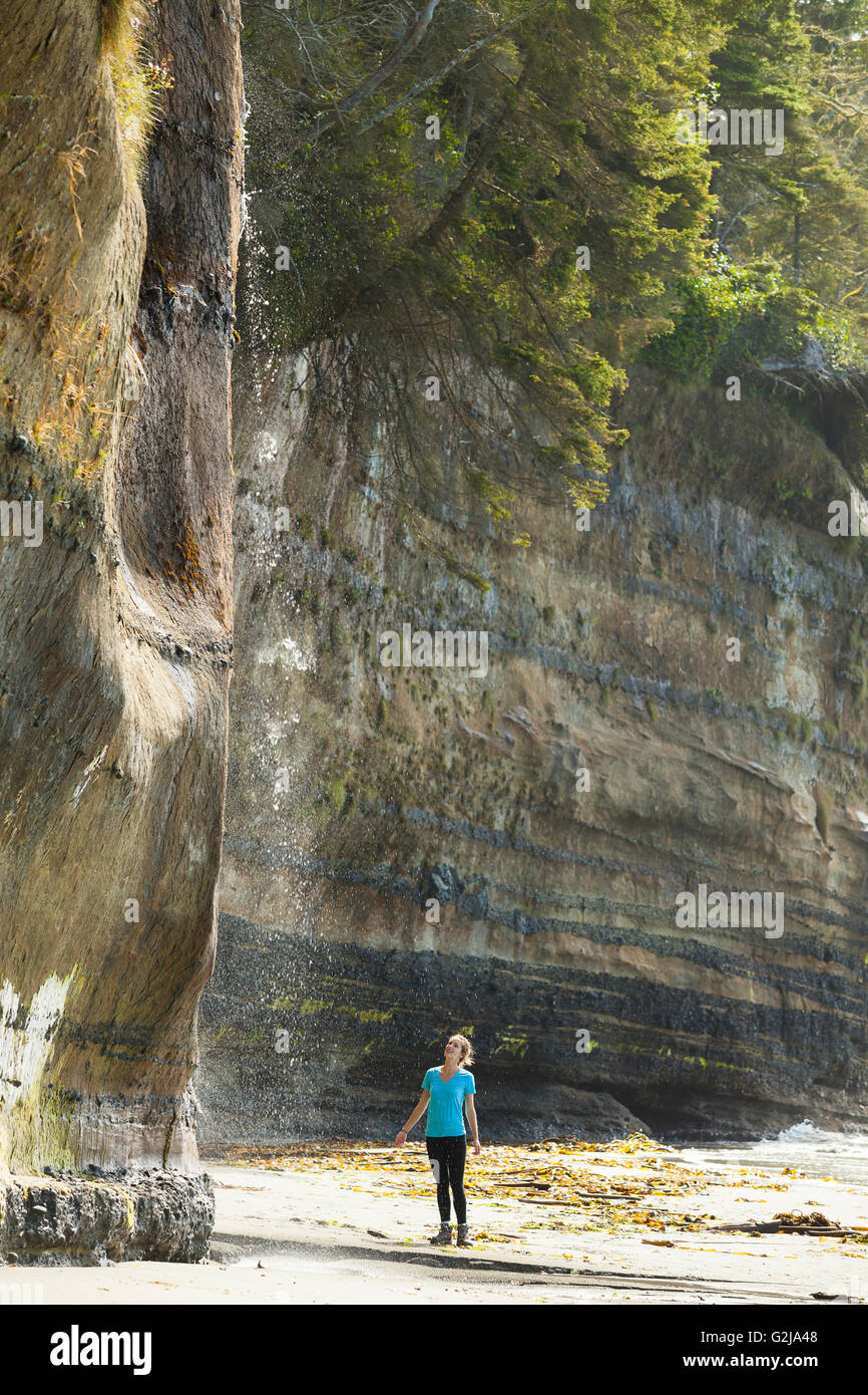 Eine junge stehend mit Wasserfall im Mystic Beach entlang der Juan de Fuca Trail. Vancouver Island, BC, Kanada. Stockfoto