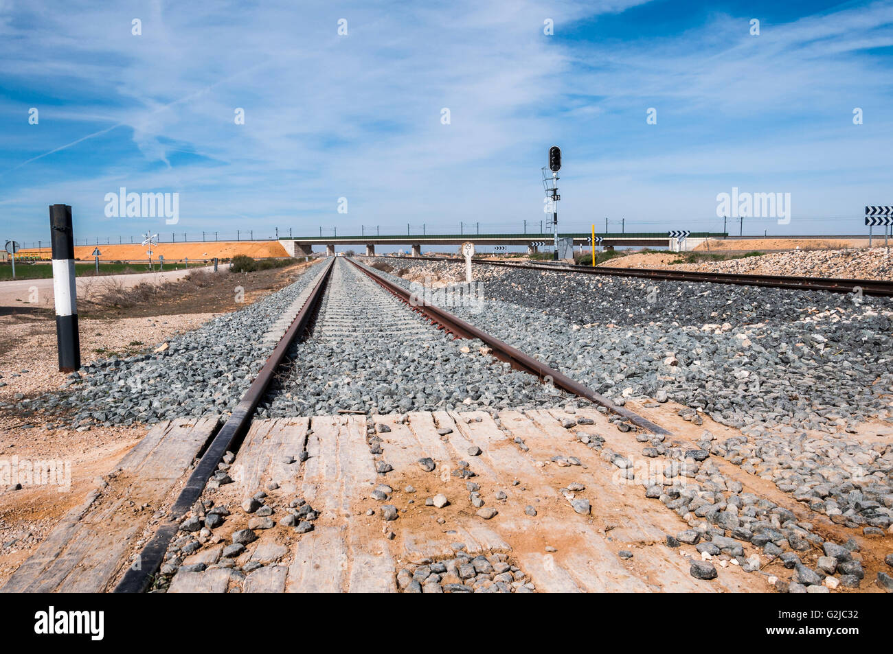 Bahnübergang ohne Barriere in der Provinz Toledo, Spanien. Im Hintergrund kann die Madrid-Levante-High-Speed-Bahn zu sehen. Stockfoto